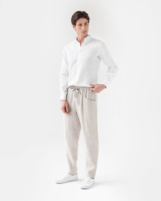 Man wearing a white shirt and light gray pants on a white background