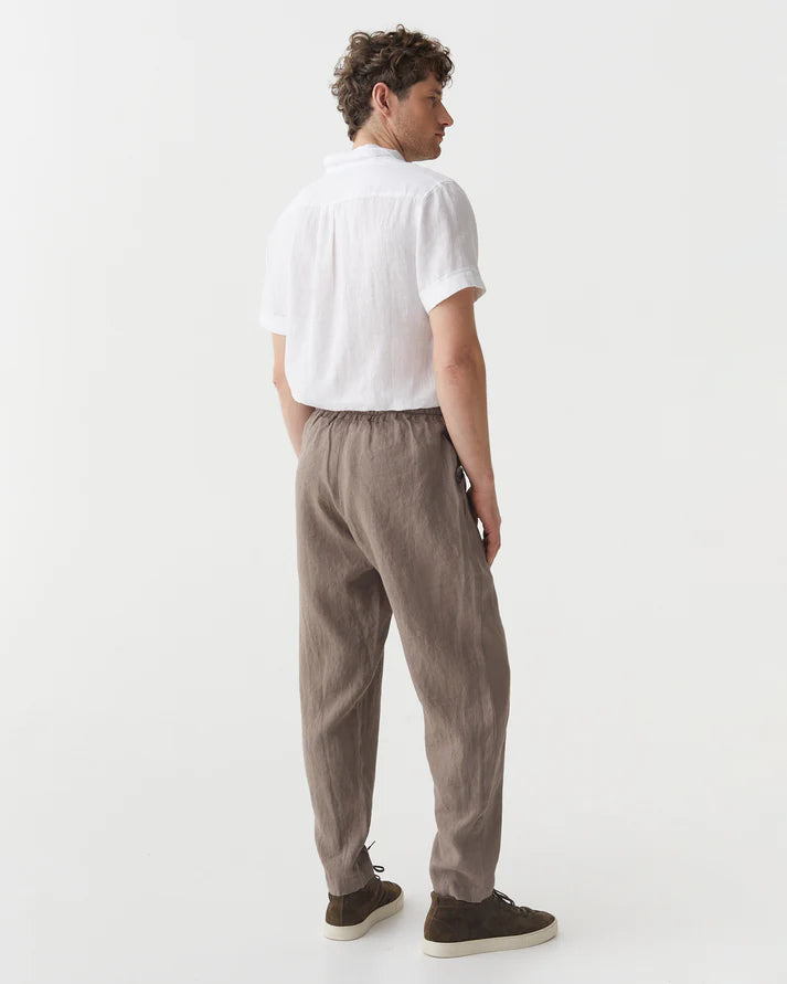 Person wearing a white shirt and brown pants on a white background