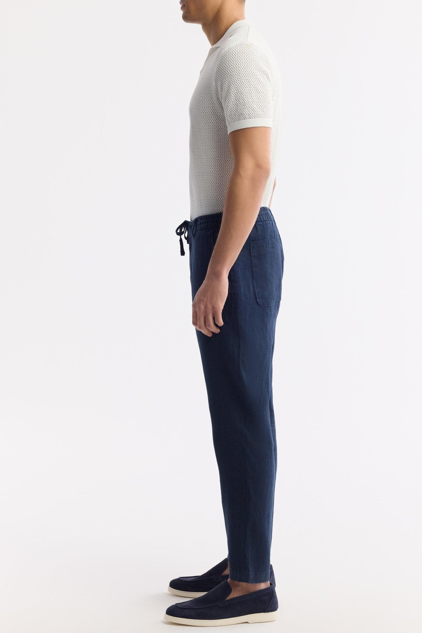 Side profile of model in blue linen pants showing tapered cut