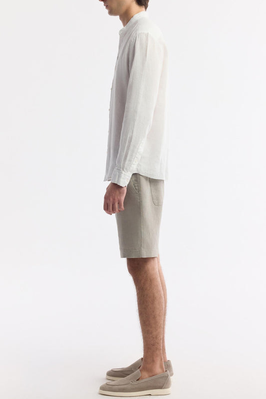 Side profile showing airy drape and tailored sleeve of white linen grandad shirt