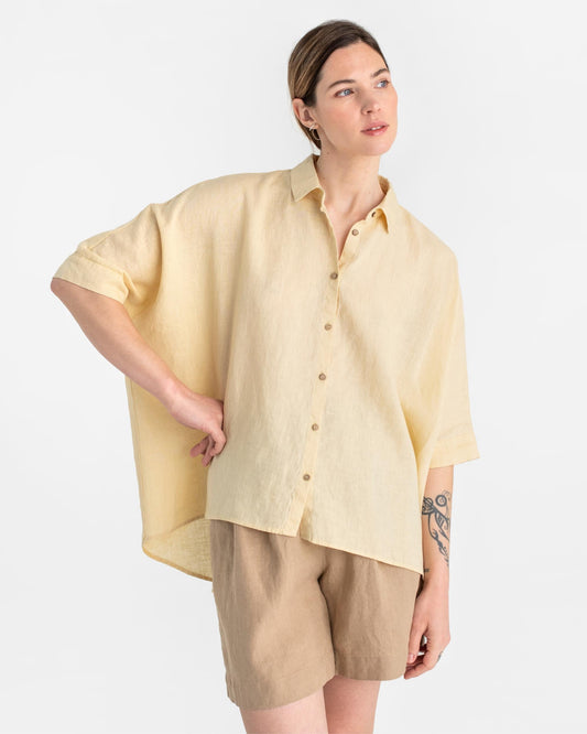 Woman wearing a light yellow shirt and beige shorts on a white background