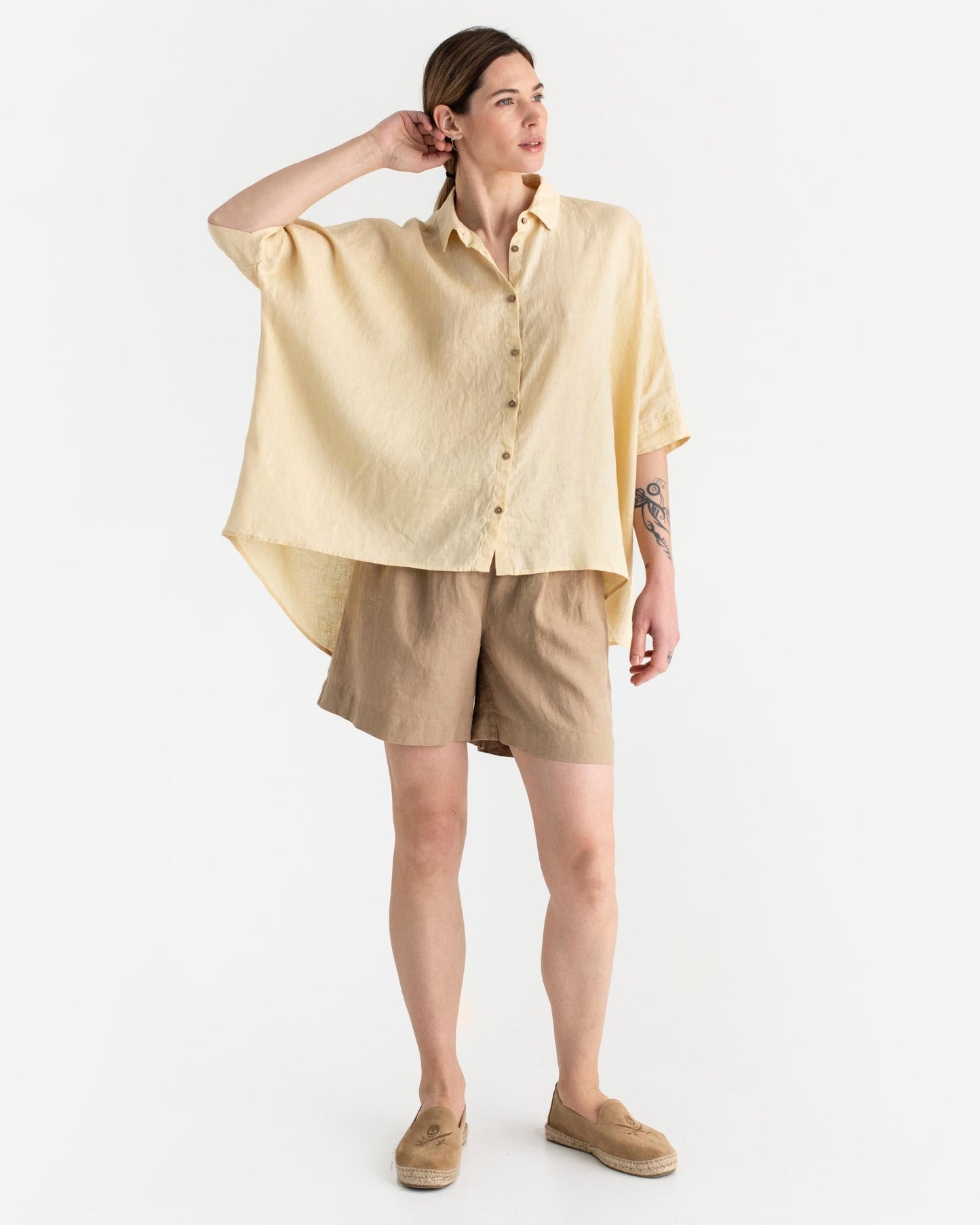 Woman wearing a light yellow shirt and beige shorts on a white background