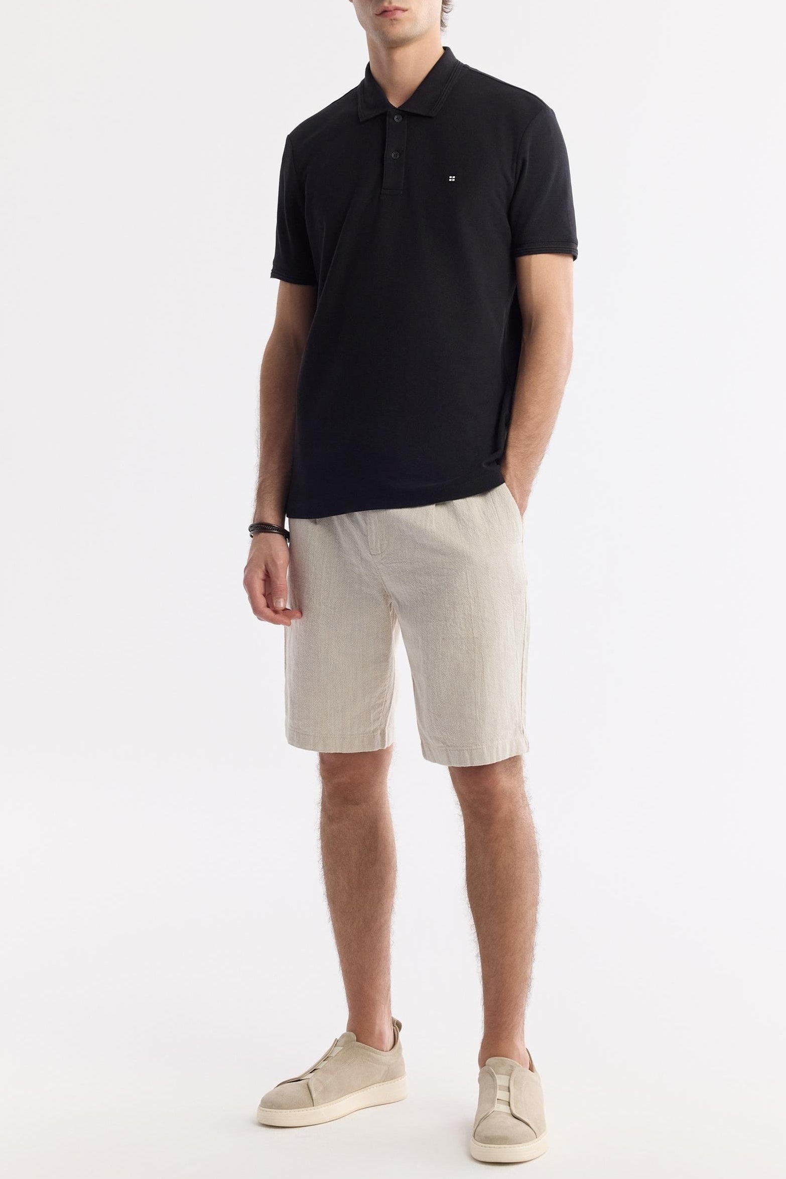 Men wearing beige linen relaxed shorts and black polo shirt – front full view
