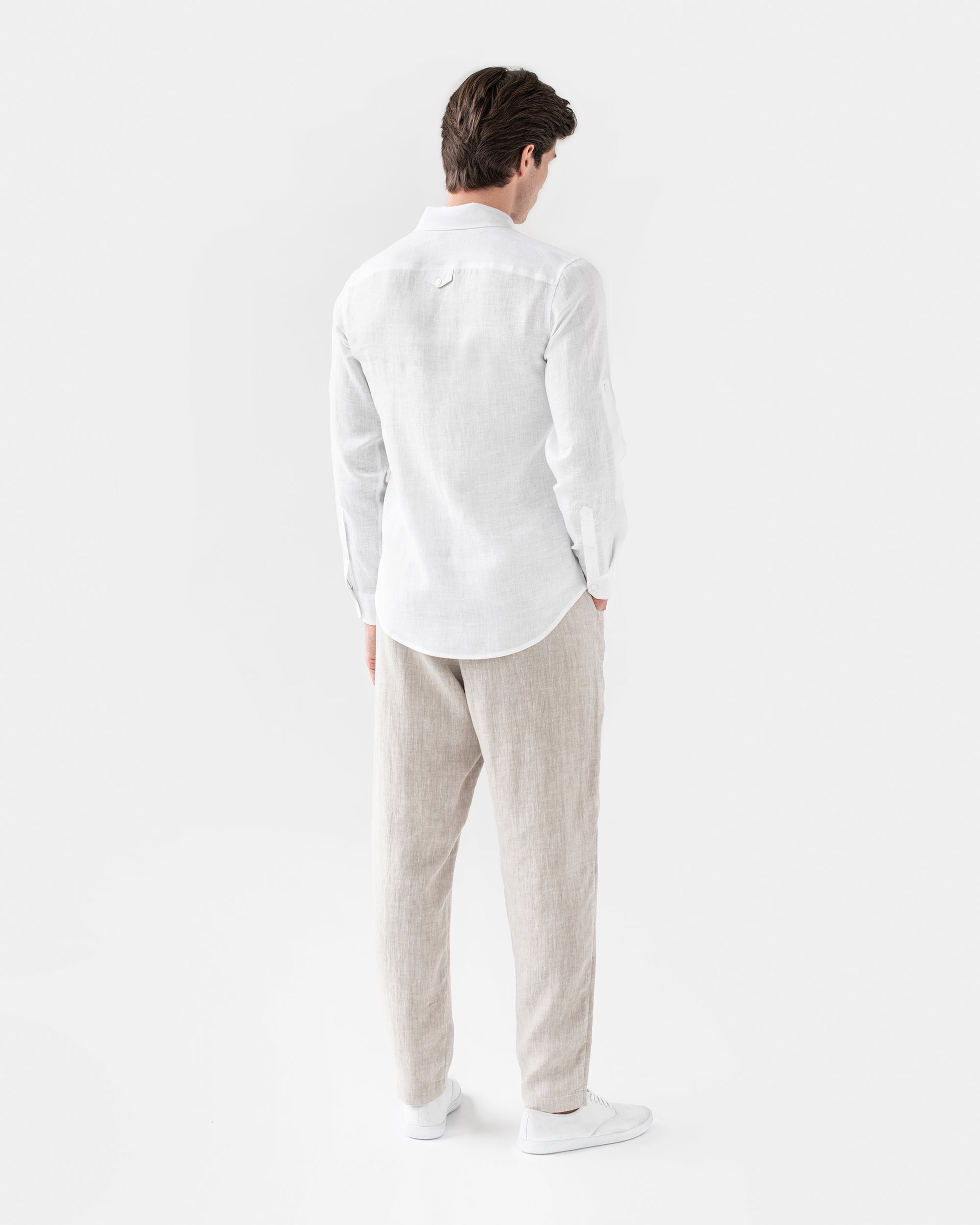 Man wearing a white shirt and beige pants on a white background