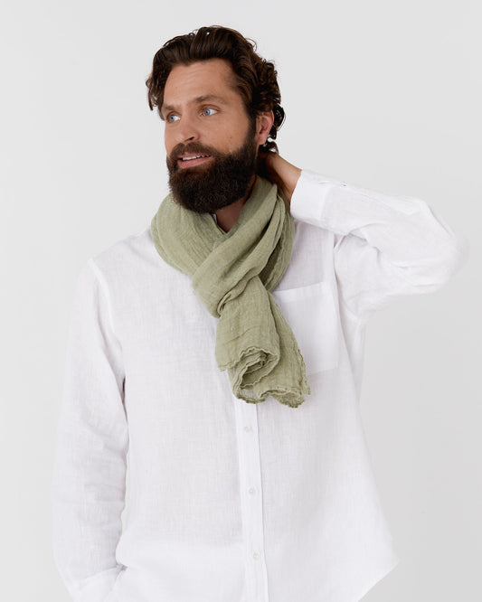 Man wearing a green scarf and white shirt against a plain background