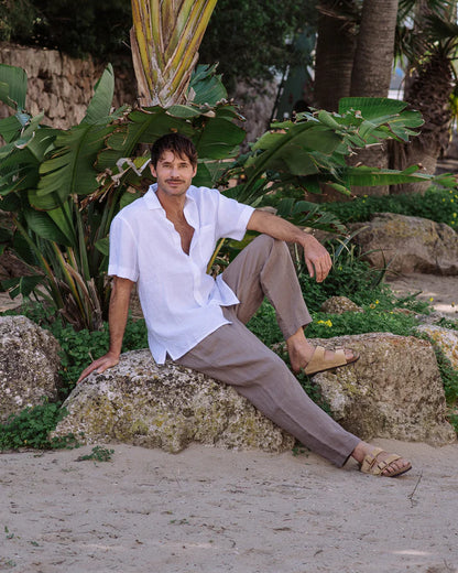 Man sitting on a rock in a garden with plants and trees in the background
