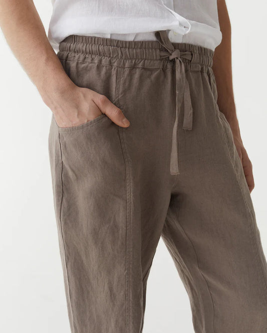 Brown pants with a tie waist worn by a person on a white background