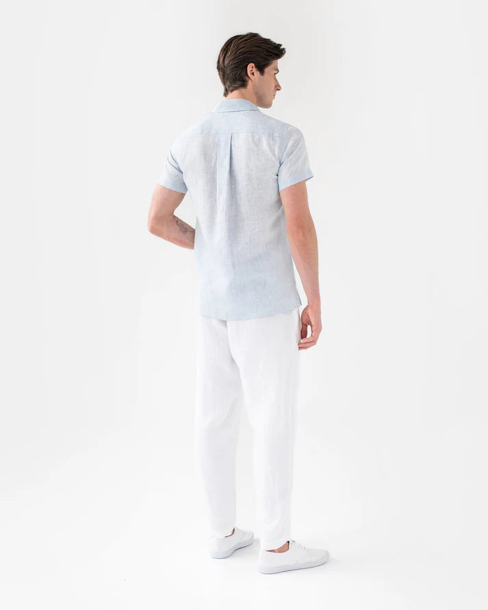 Man wearing a light blue polo shirt and white pants on a white background
