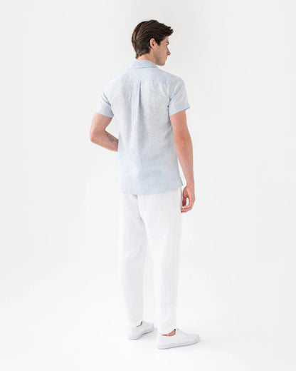 Man wearing a light blue polo shirt and white pants on a white background
