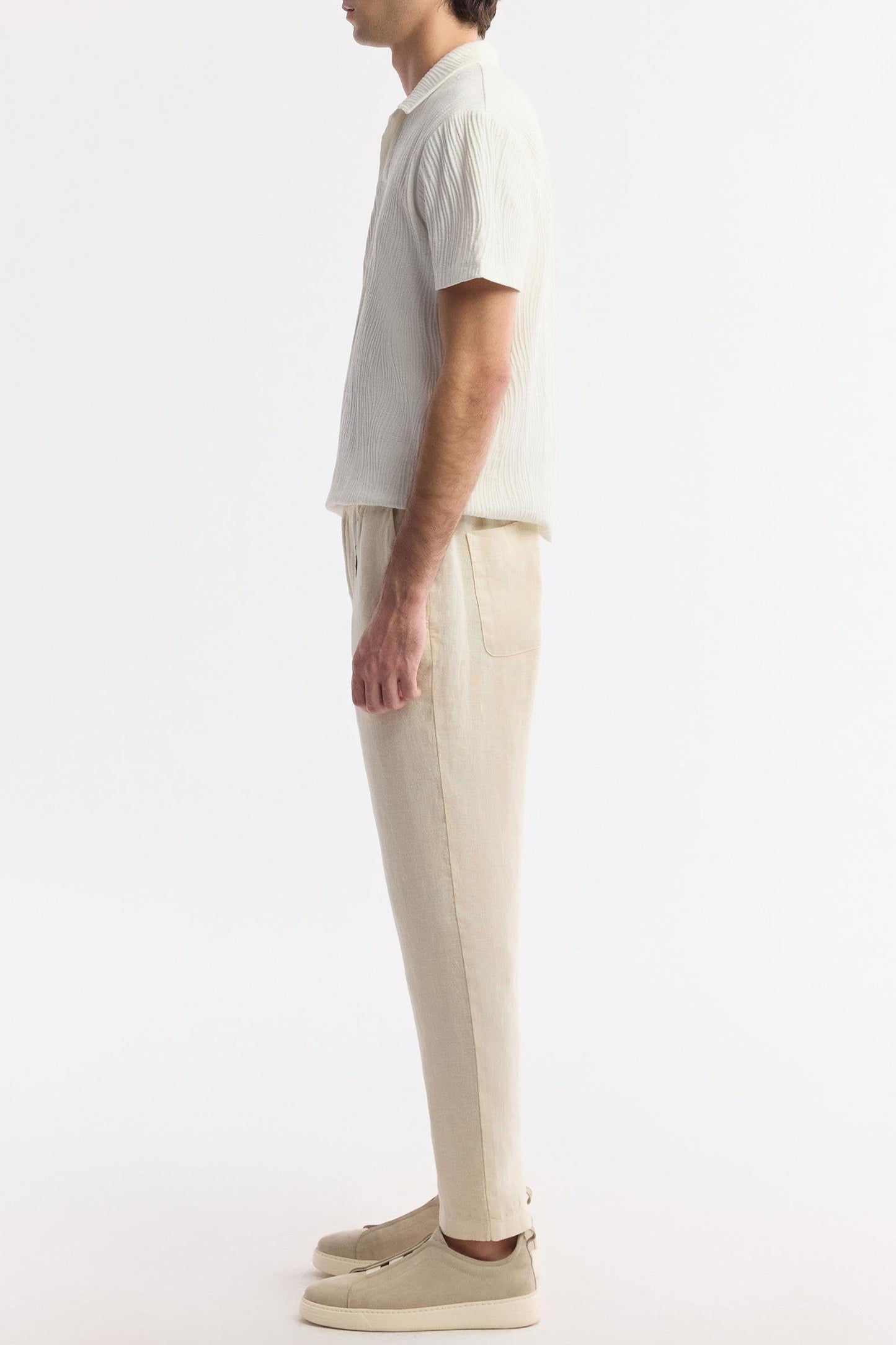Side profile of model wearing beige linen pants
