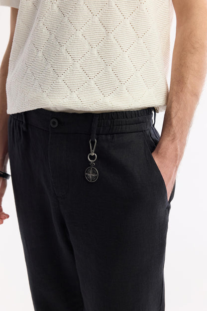 Close-up on waistband and keychain accessory in black linen pants