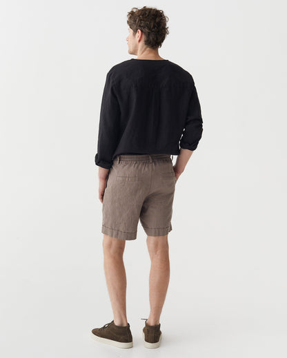 Man wearing a black sweater and taupe shorts on a white background
