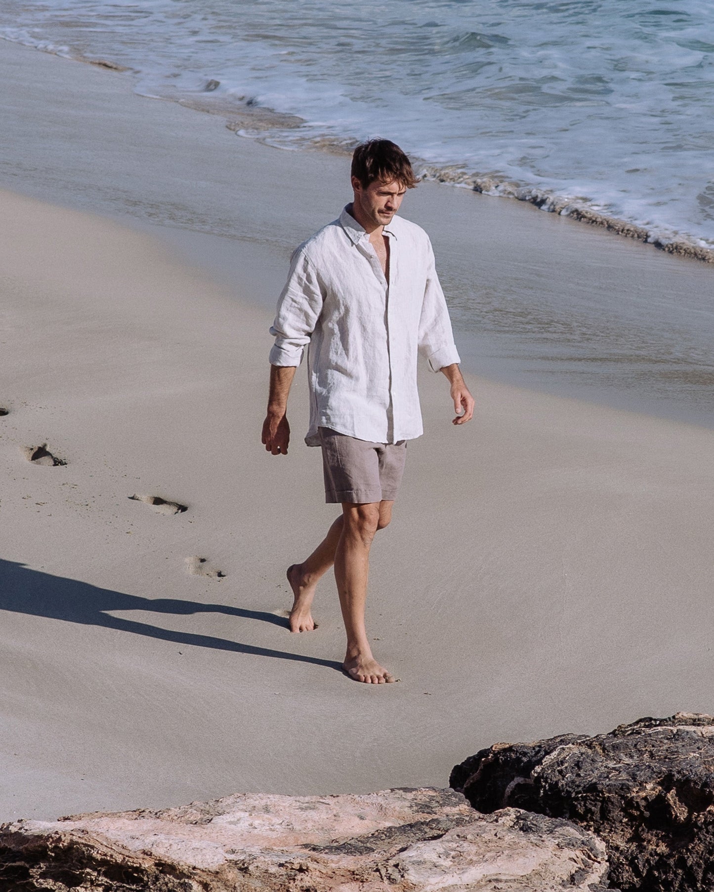 Man walking on a sandy beach with ocean waves in the background
