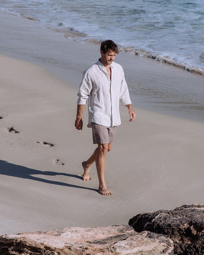 Man walking on a sandy beach with ocean waves in the background