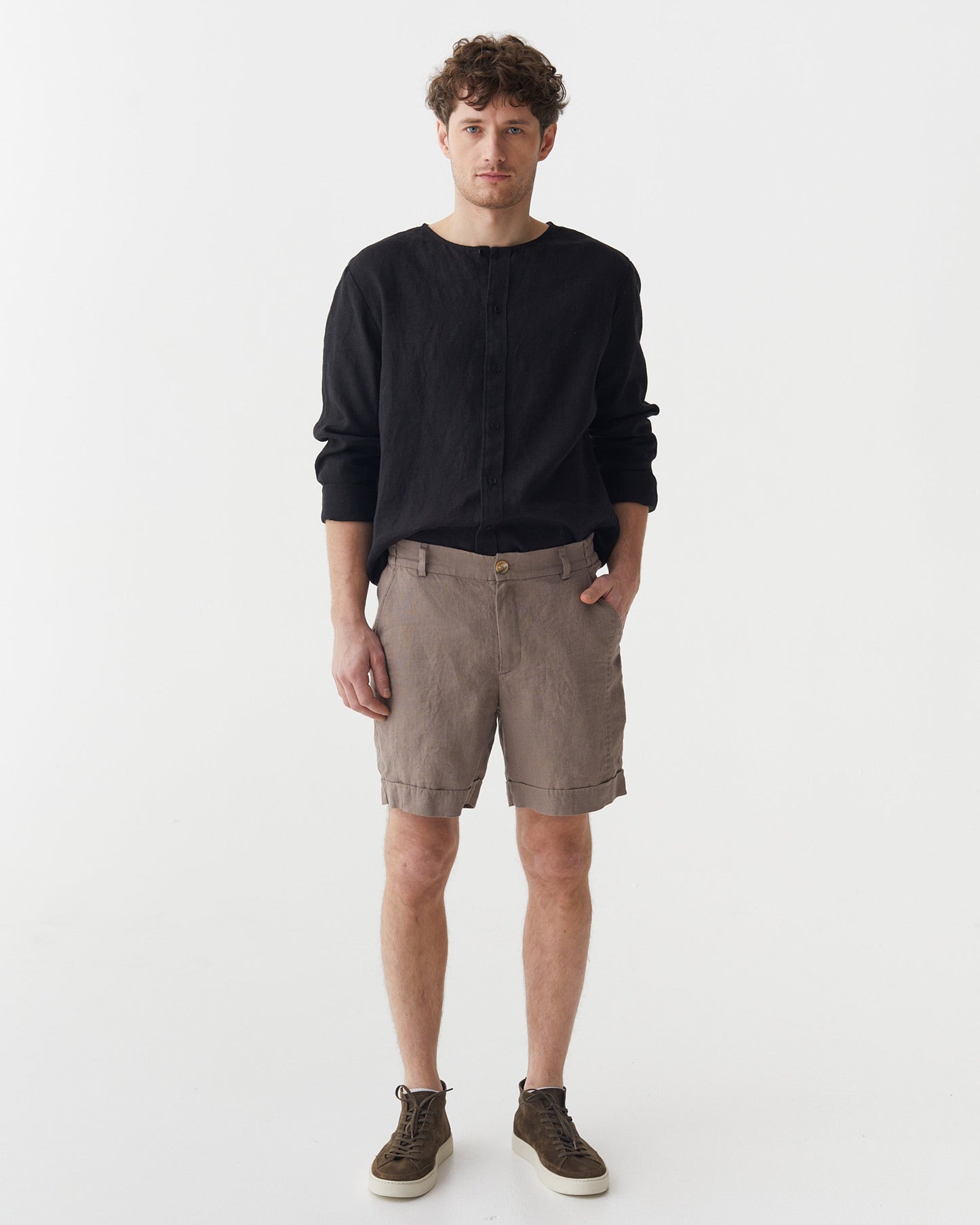 Man wearing a black sweater and brown shorts on a white background