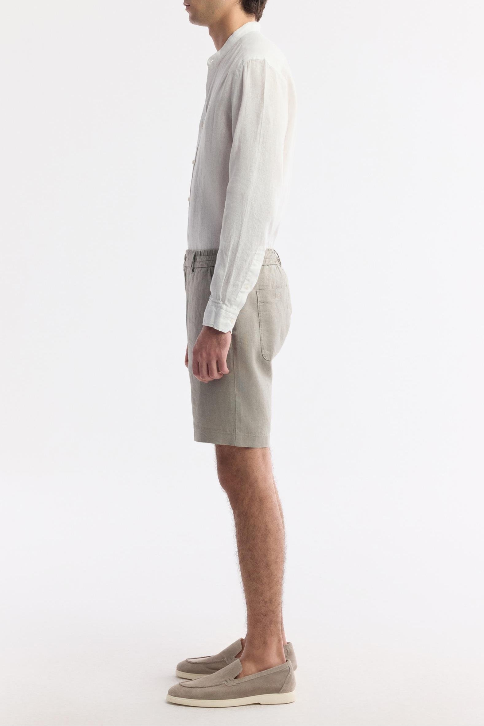 Side profile of gray linen shorts showcasing cut, structure, and natural drape of fabric