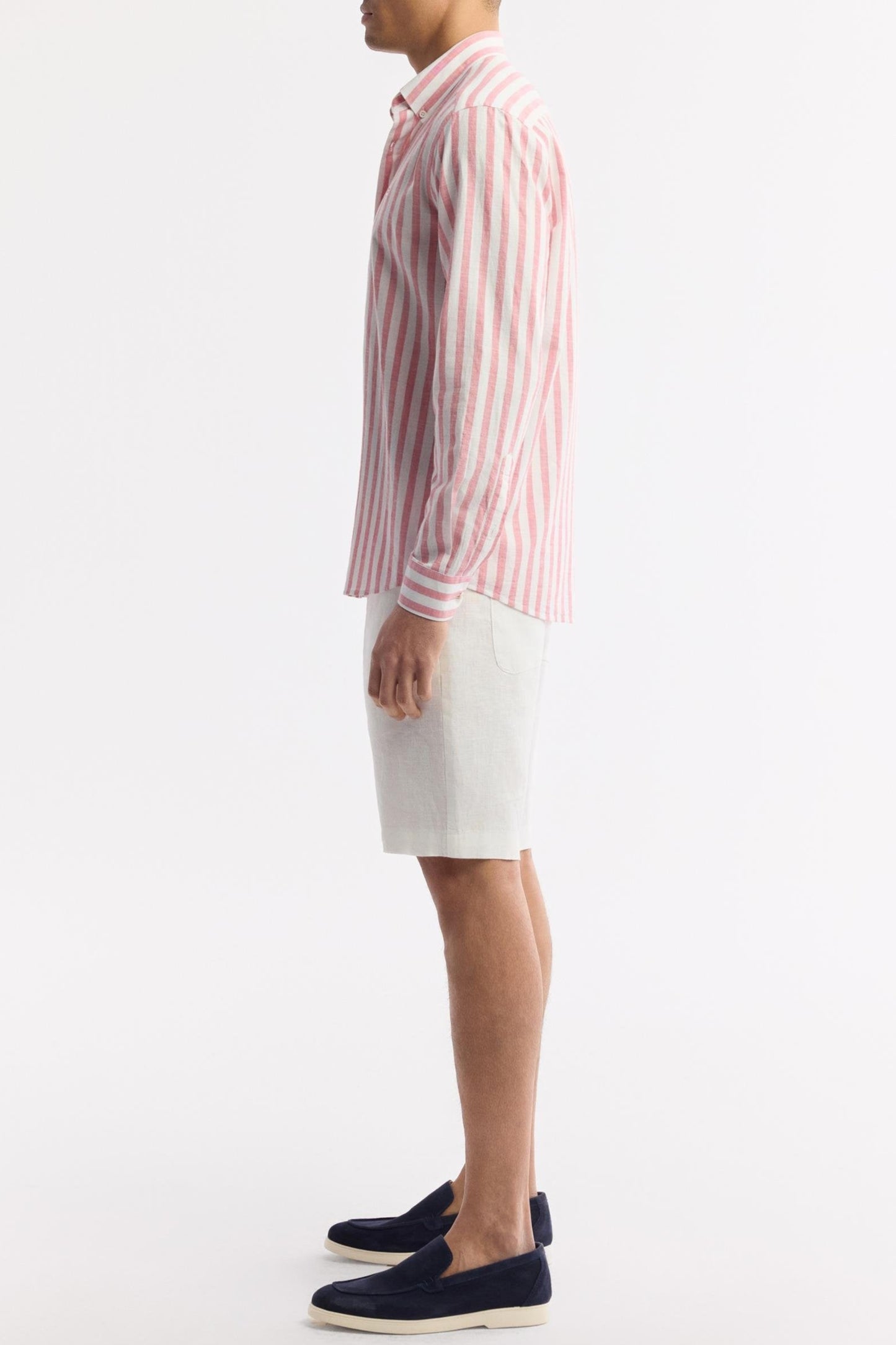 Side profile wearing pink striped cotton shirt and shorts