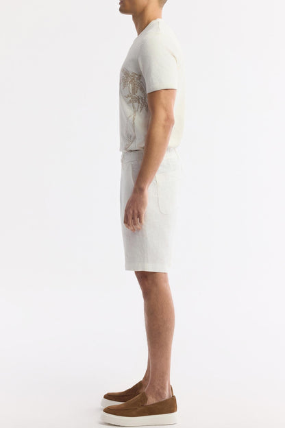 Model side view showcasing relaxed fit of white linen shorts