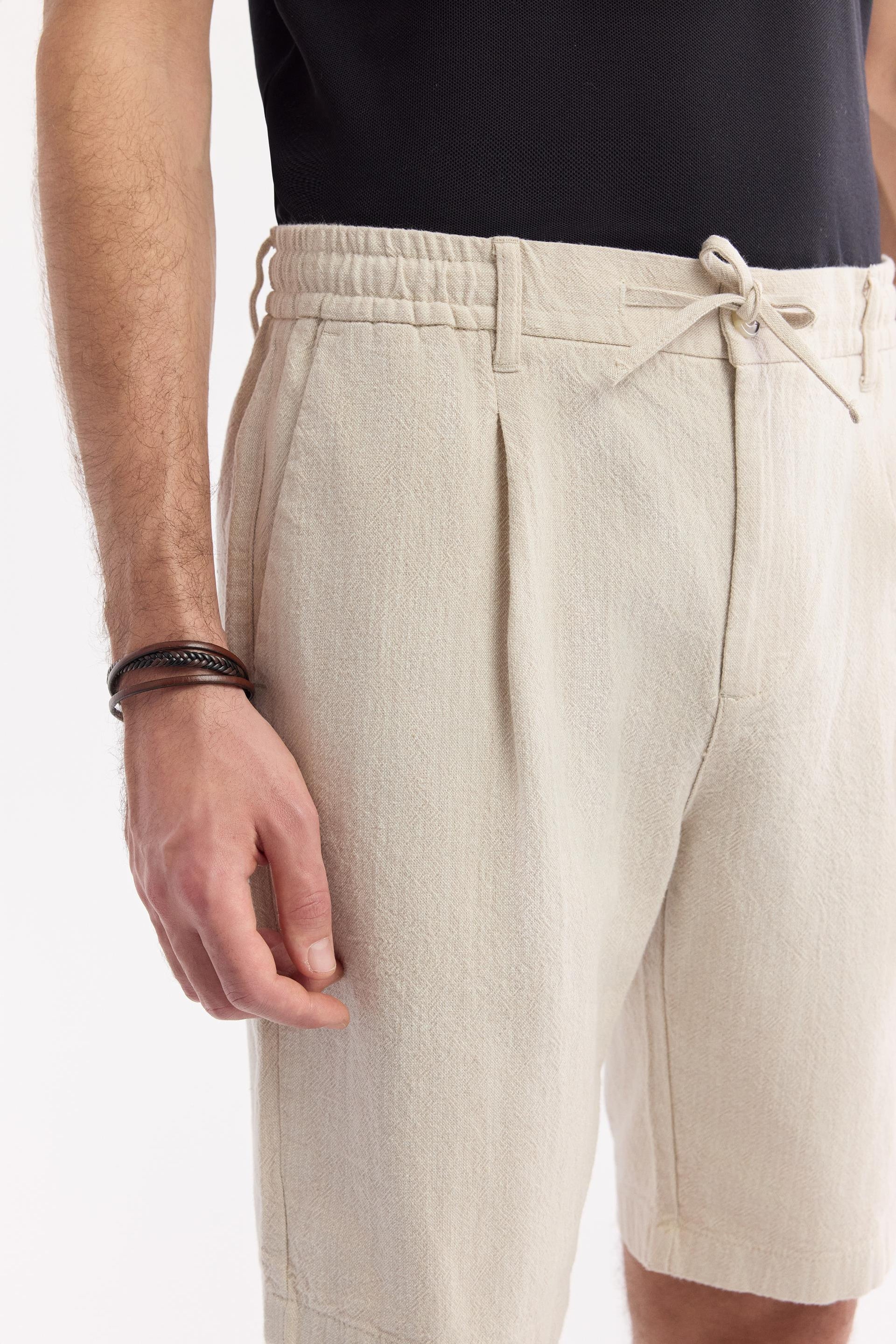 Close-up detail of fabric texture and hem of beige linen shorts