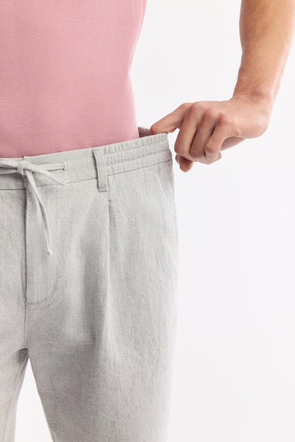 Hand stretching elastic waistband on men’s gray linen shorts – Swiftyle