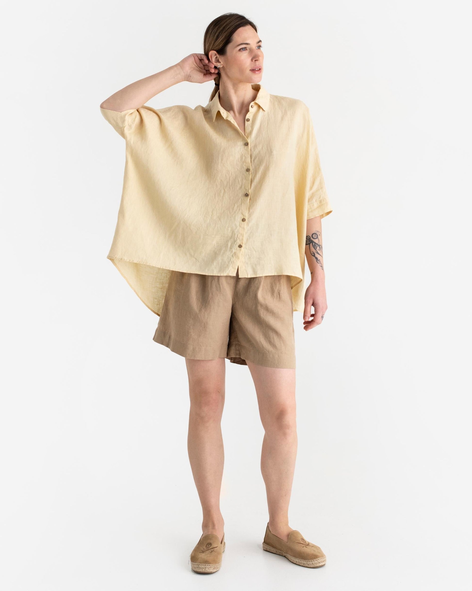 Woman wearing a light yellow shirt and beige shorts on a white background