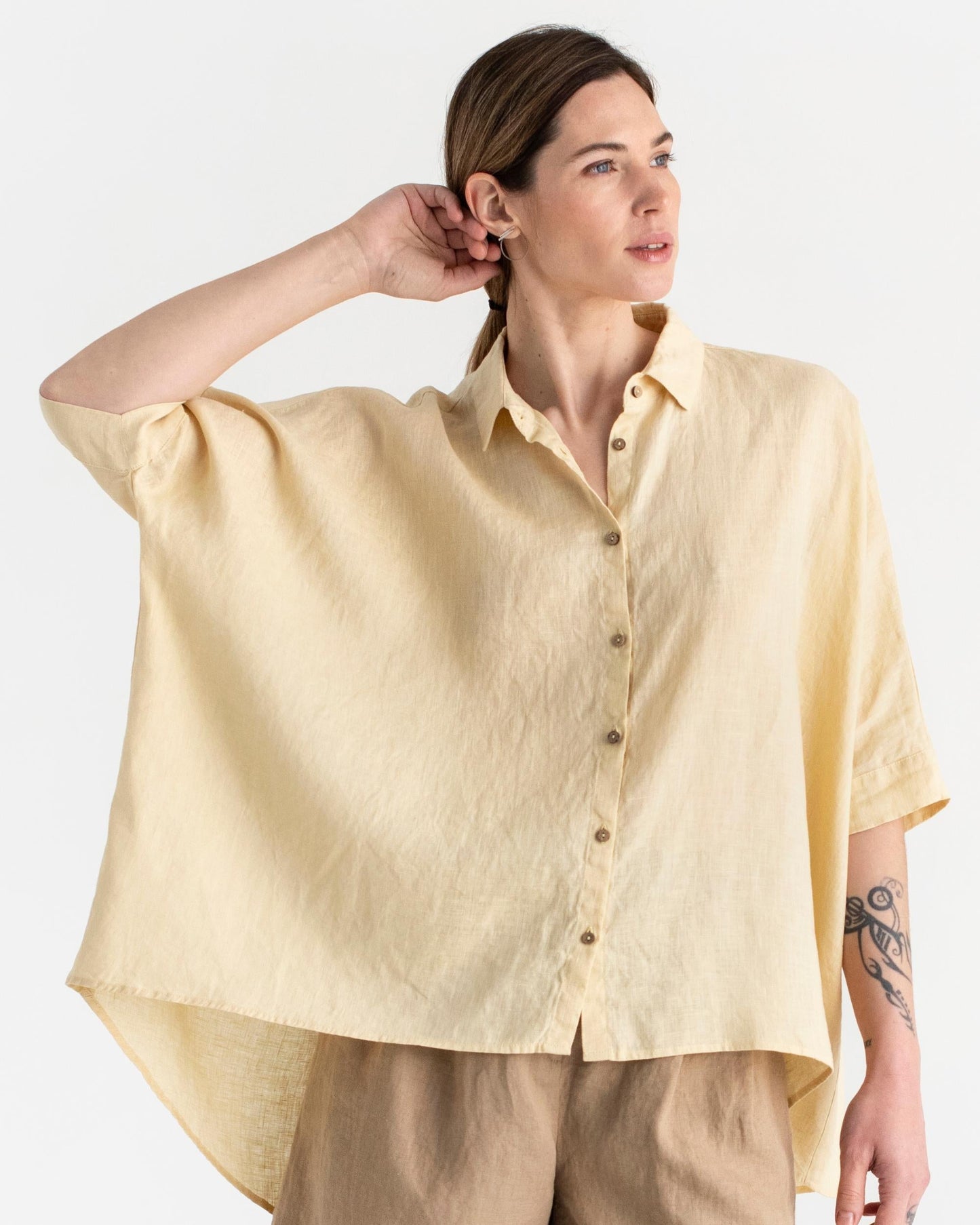 Woman wearing a light yellow shirt with a plain background