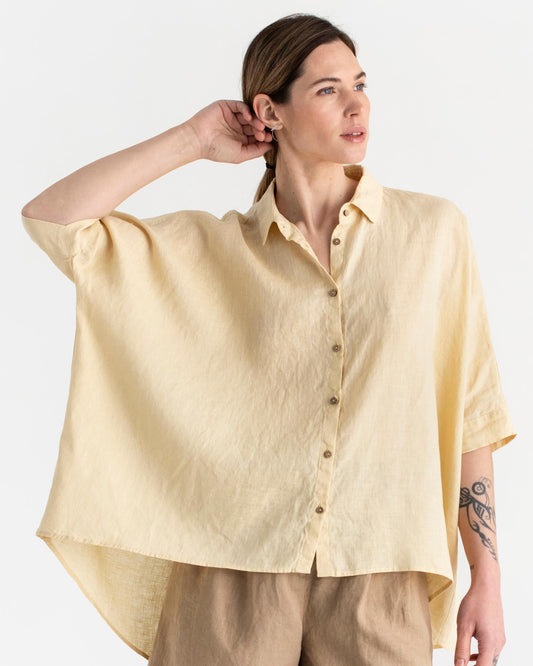Woman wearing a light yellow shirt with a plain background