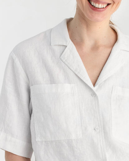 Person wearing a white shirt with a collar on a plain background