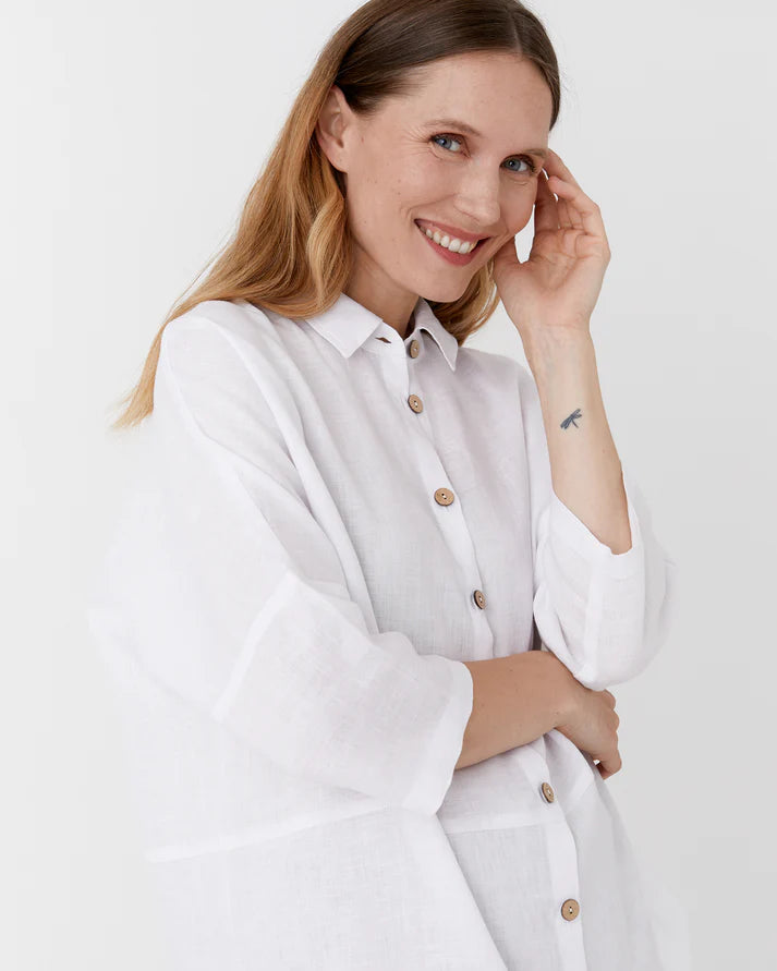 Woman wearing a white shirt with buttons on a plain background