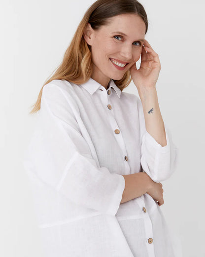 Woman wearing a white shirt with buttons on a plain background