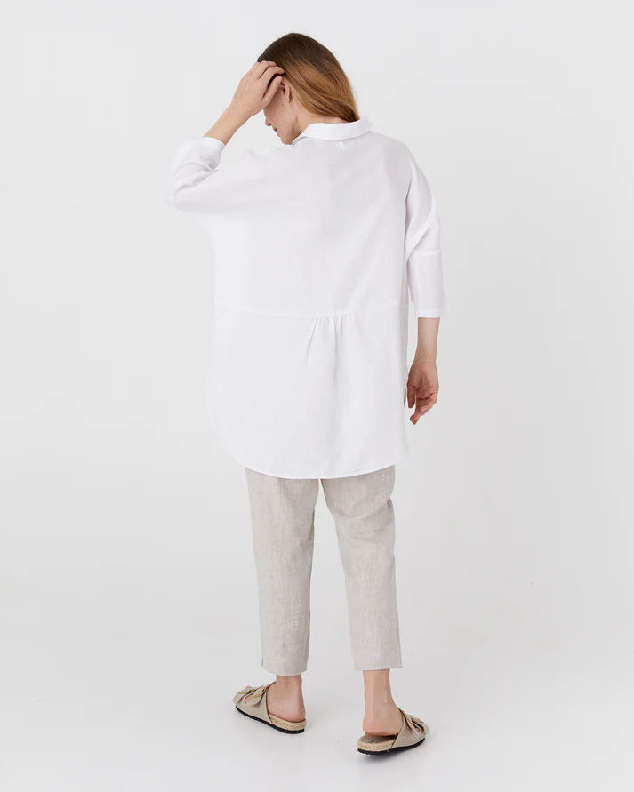 Woman wearing a white shirt and light gray pants on a white background