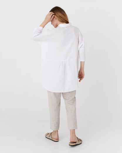 Woman wearing a white shirt and light gray pants on a white background